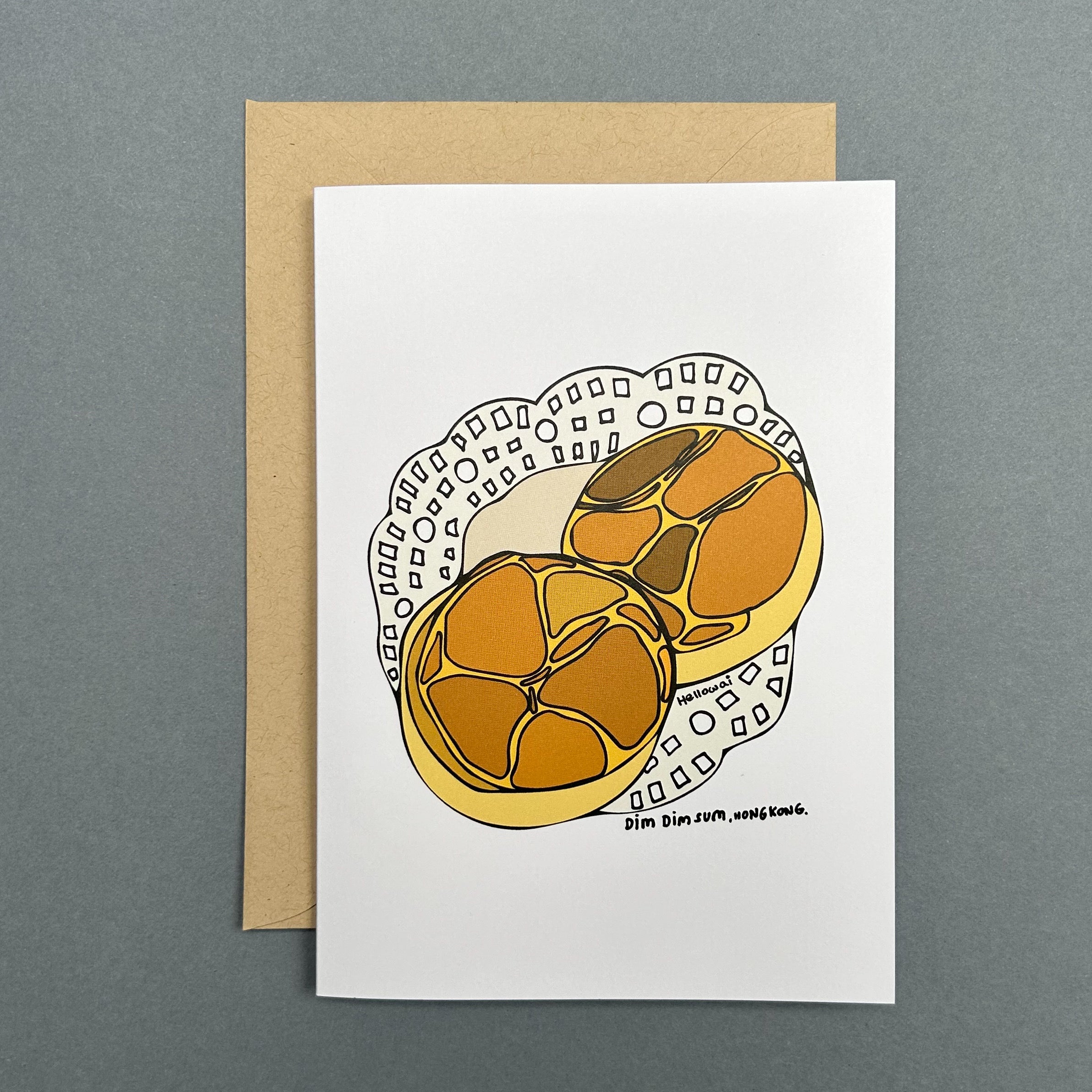 An A6 Hello Wai folded greeting card with a colour illustration of two bolo bao on a paper doily napkin, printed on white card. The card is placed on top of a brown envelope.