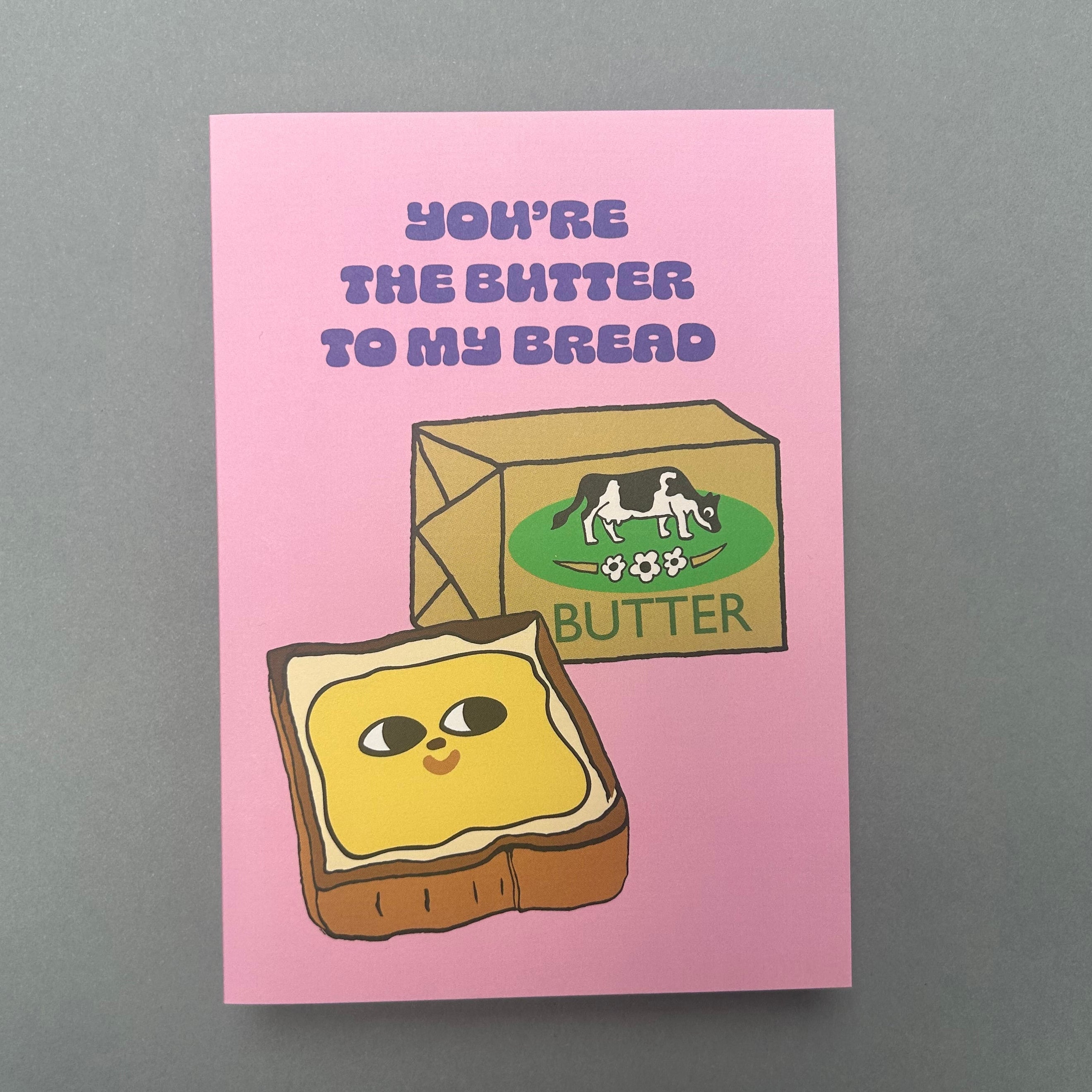 Card with cartoon toast and butter packaging on a pink background with text.