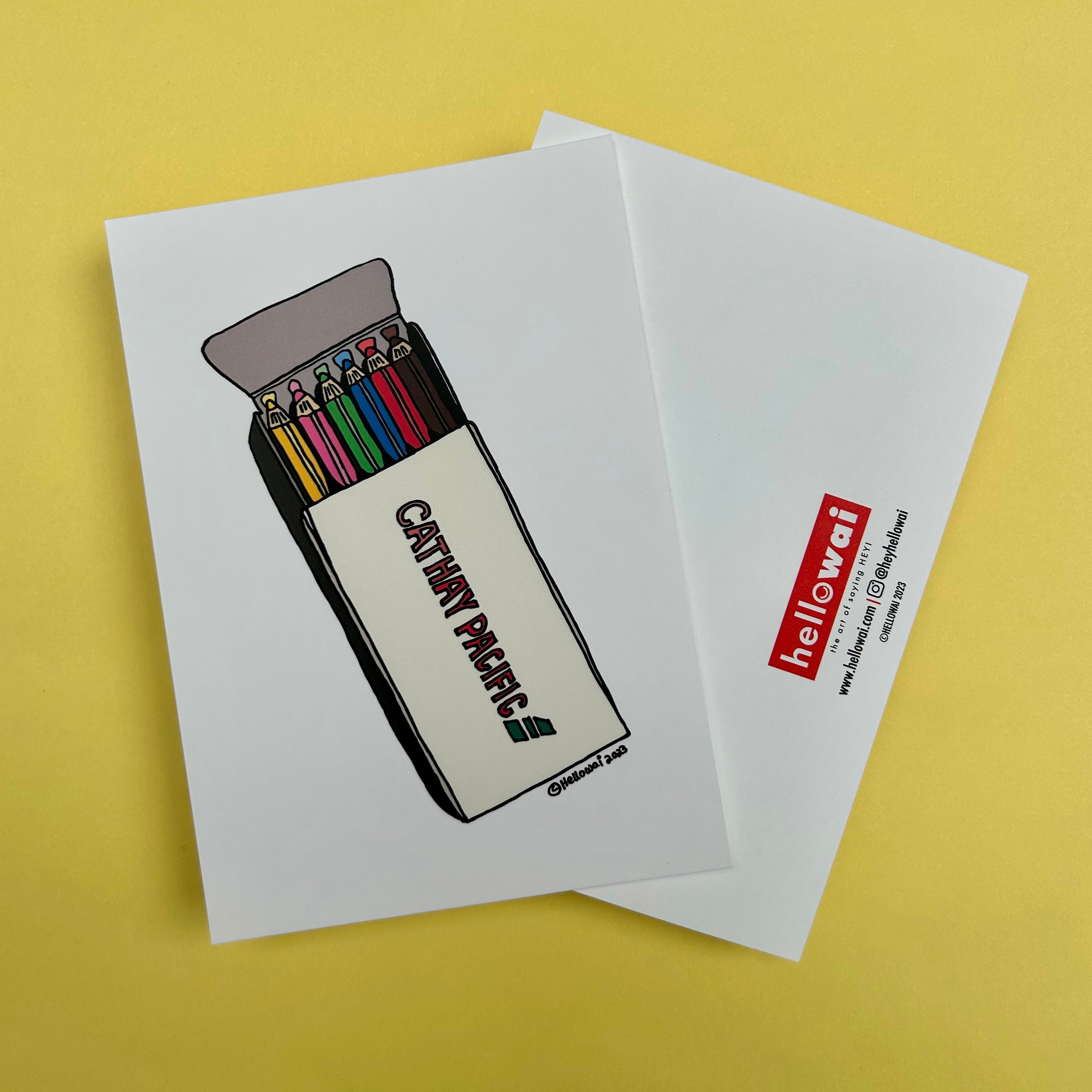 Front and back view of an A6 Hello Wai flat notecard. Front has colour illustration of an opened box of colouring pencils, printed on white card. Back has the Hello Wai logo.
