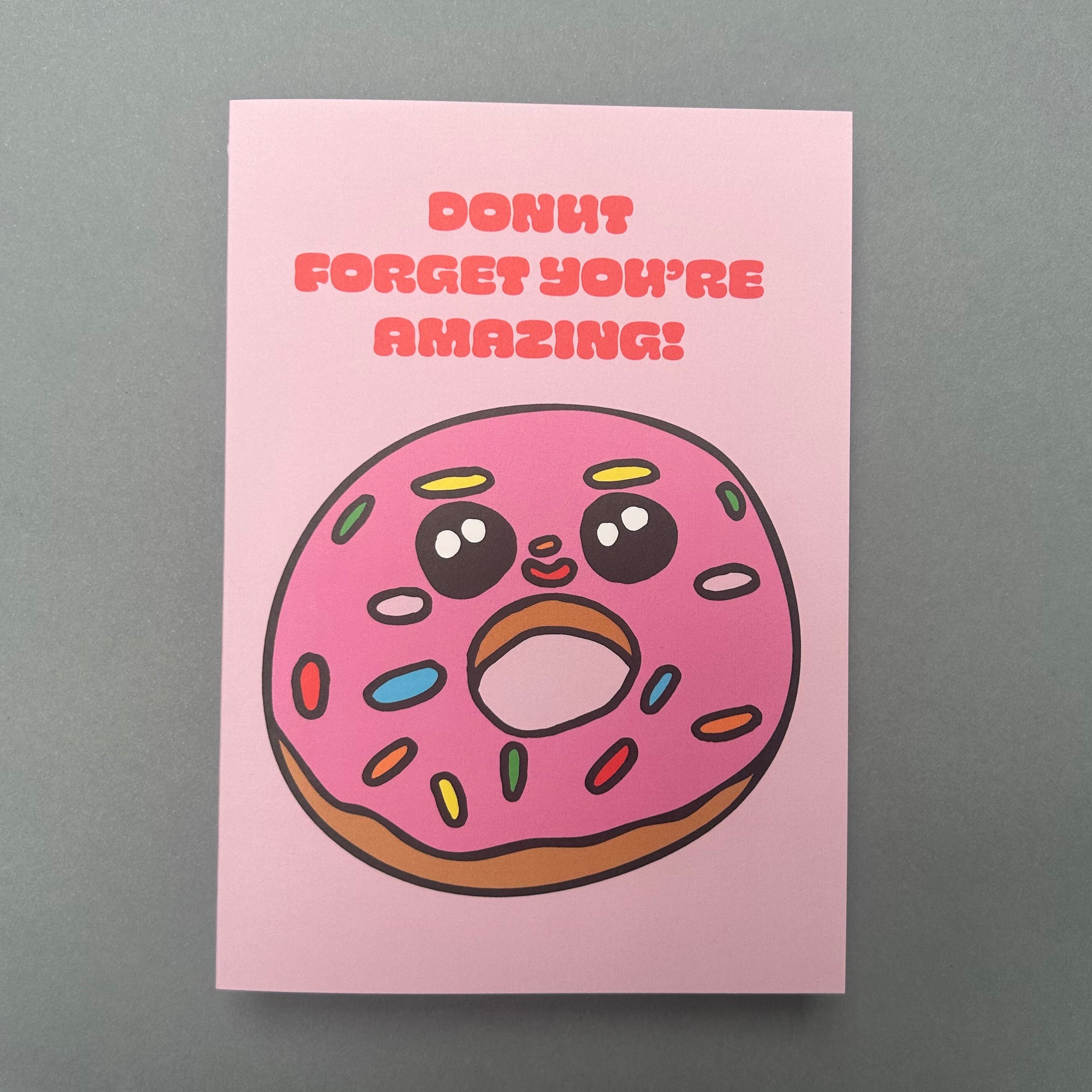 Card with a cartoon donut and text 'Don't forget you're amazing!' on a pink background