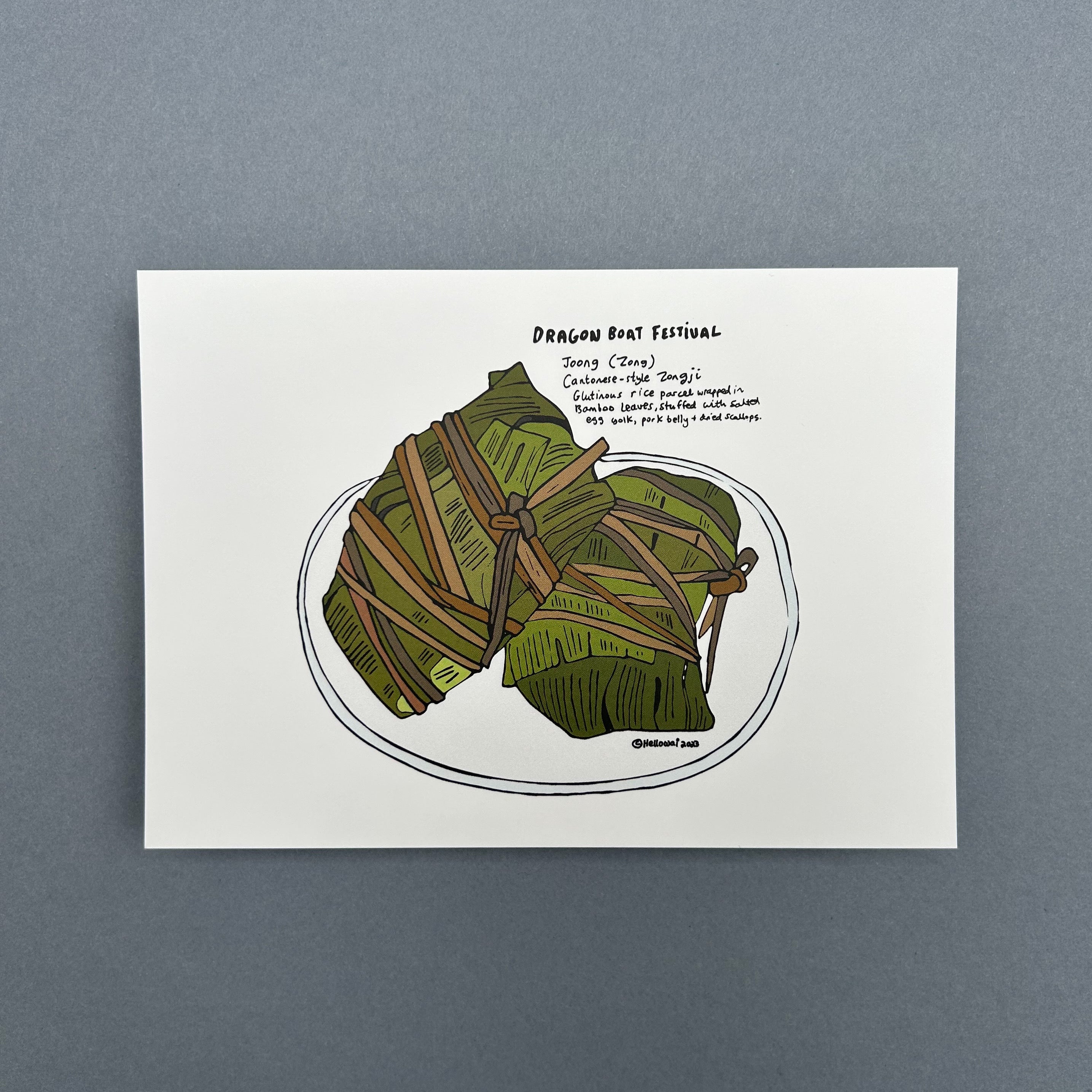An A6 Hello Wai flat notecard with a colour illustration of two glutinous rice parcels wrapped in bamboo leaves on a plate and some handwritten text describing a Dragon Boat Festival food tradition, printed on white card.