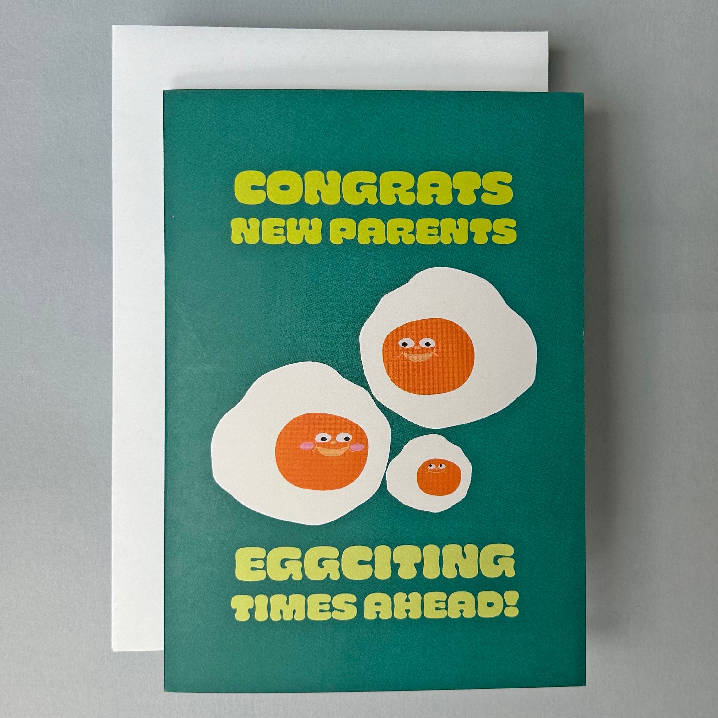Greeting card with cartoon eggs and text 'Congrats New Parents, Eggciting Times Ahead!' on a green background.