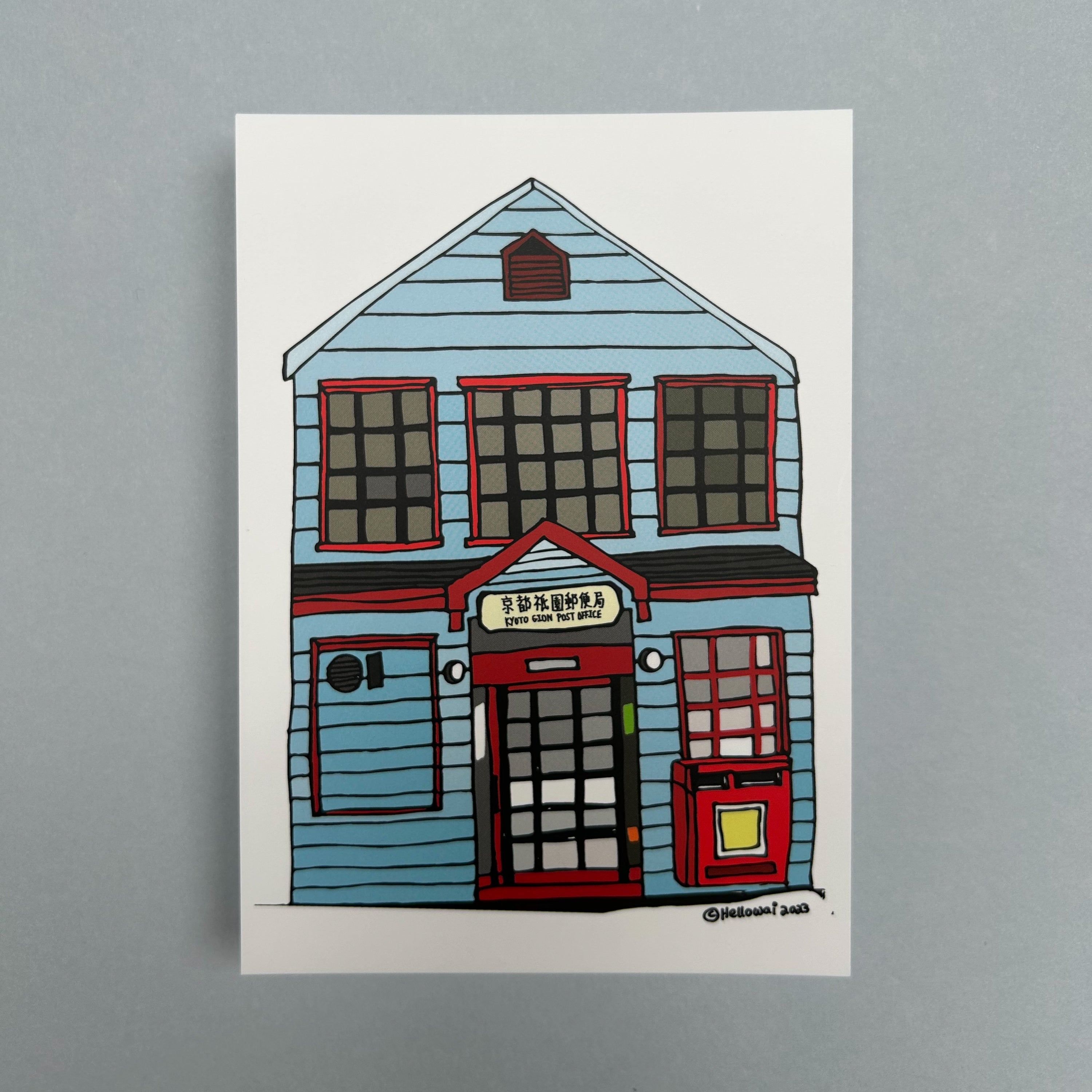 An A6 Hello Wai flat notecard with a colour illustration of a light blue building with a sign saying Kyoto Gion Post Office above the front door, printed on white card.