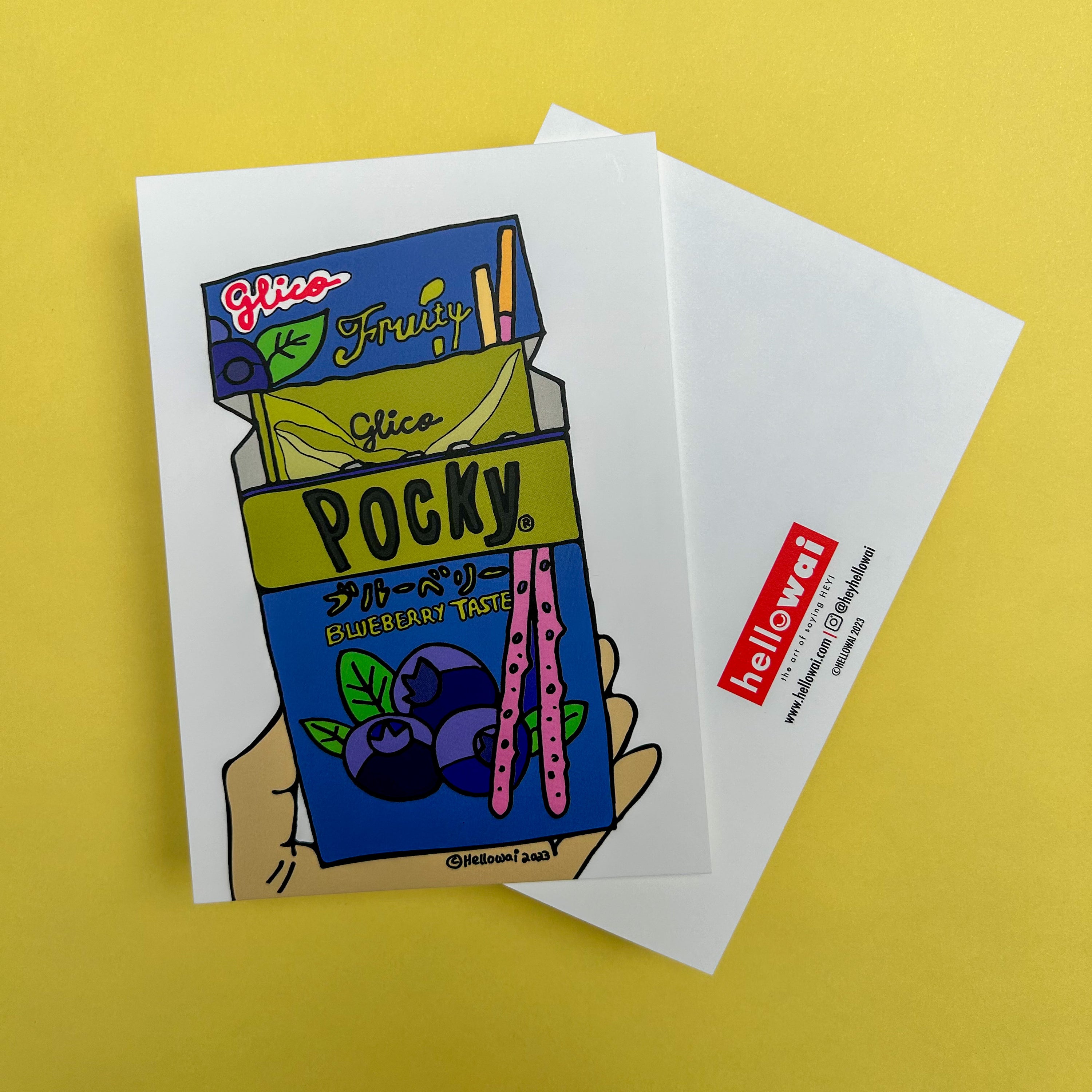 Front and back view of an A6 Hello Wai flat notecard. Front has colour illustration of a hand holding an opened box of Blueberry Taste Pocky. Back has the Hello Wai logo.