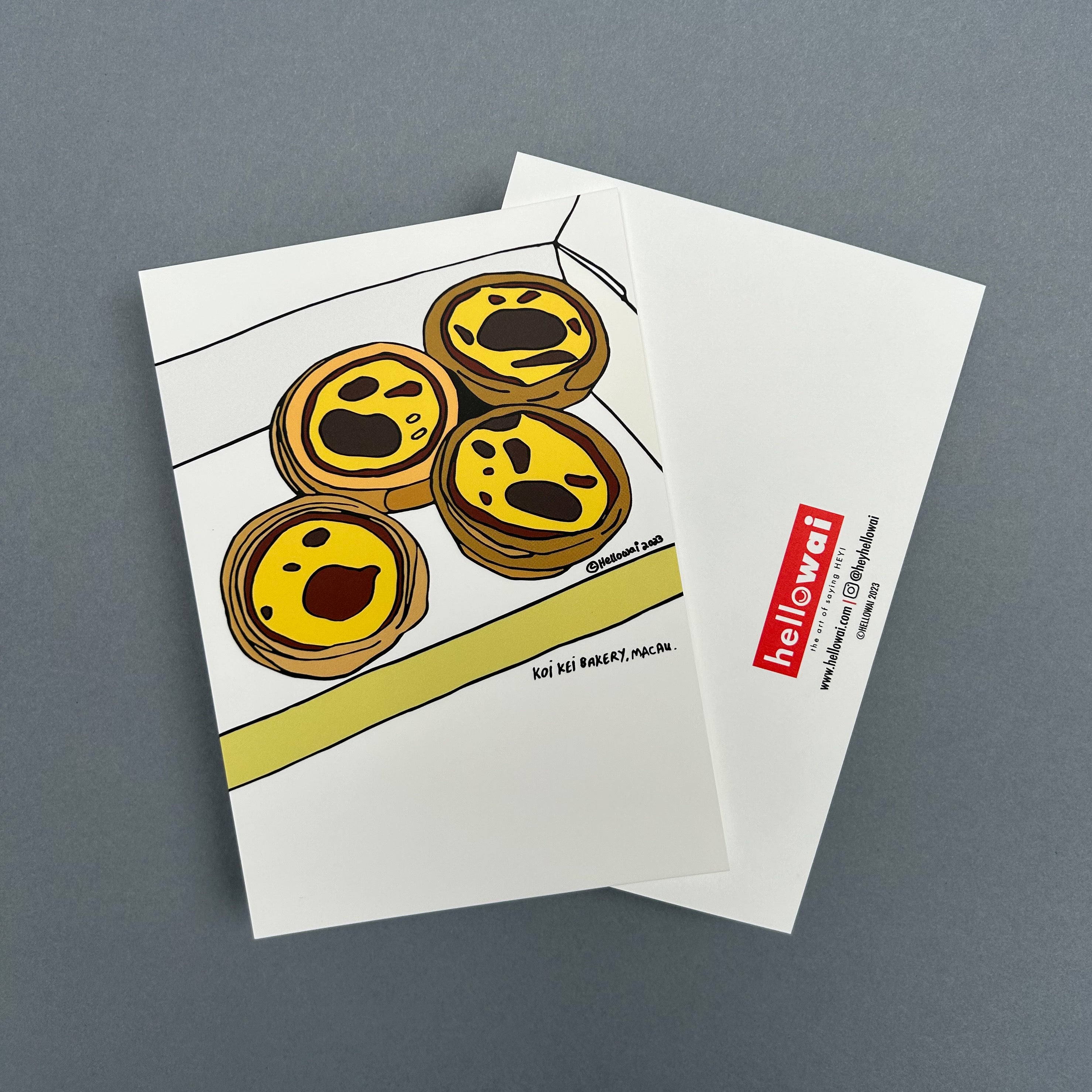 Front and back view of an A6 Hello Wai flat notecard. Front has colour illustration of four Portuguese egg tarts in an open box. Back has the Hello Wai logo.