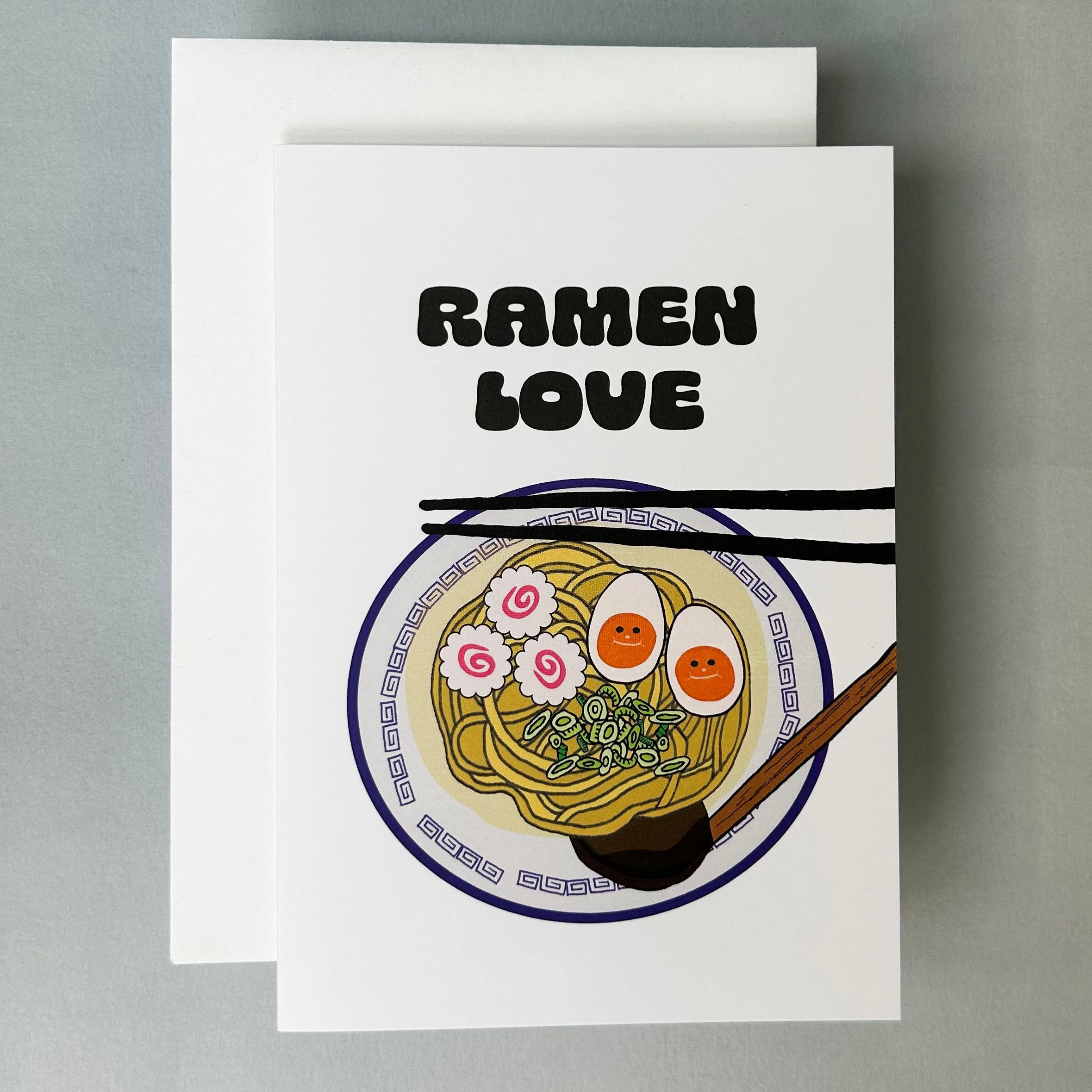 Greeting card with 'Ramen Love' text and illustration of ramen noodles, eggs, fishcake on a white background.