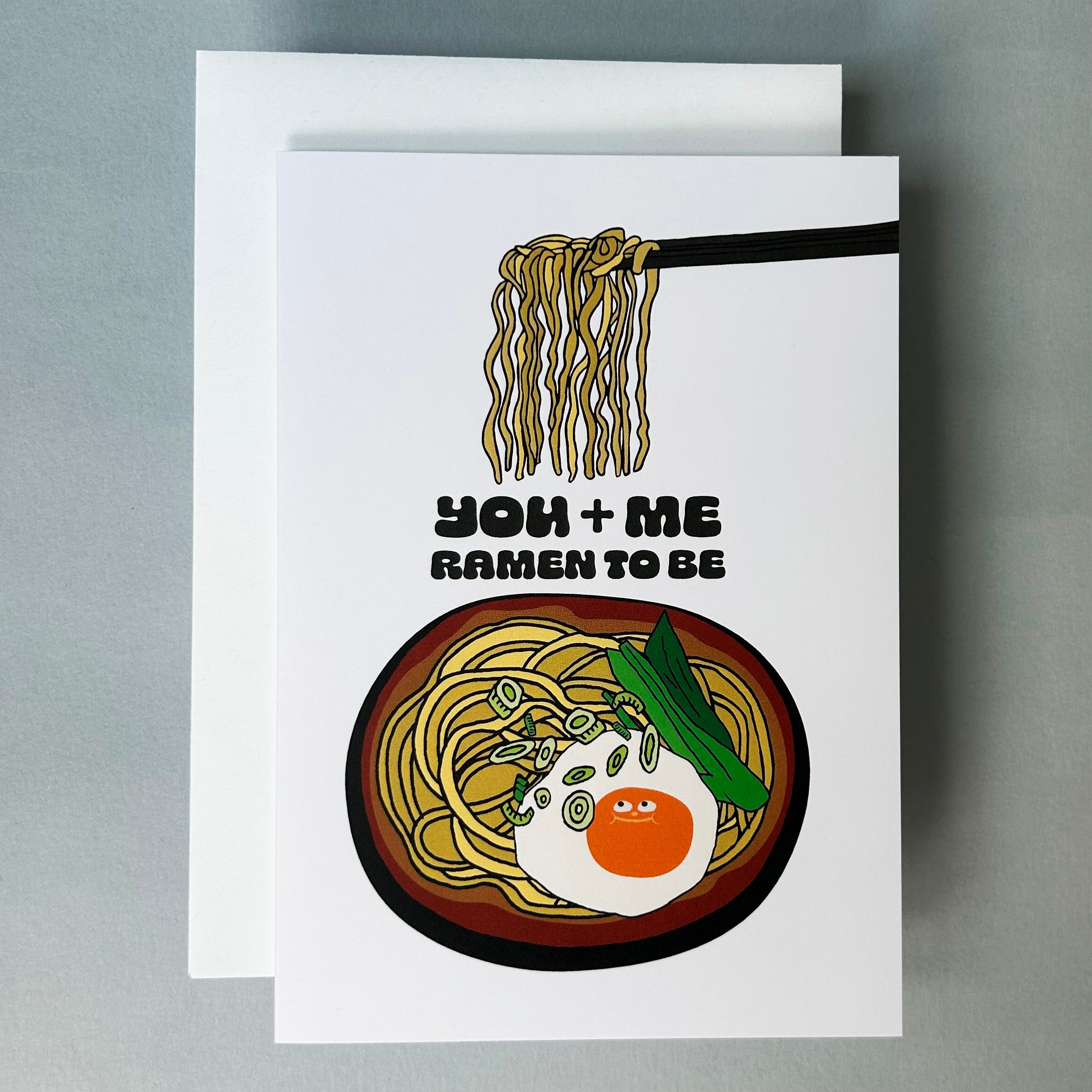 Greeting card with ramen illustration and text: You and Me Ramen To Be" and a smiley egg on a white background. 